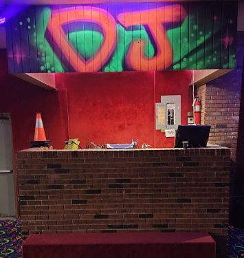 Neon sign displaying the text "DJs" illuminated in a lobby setting.